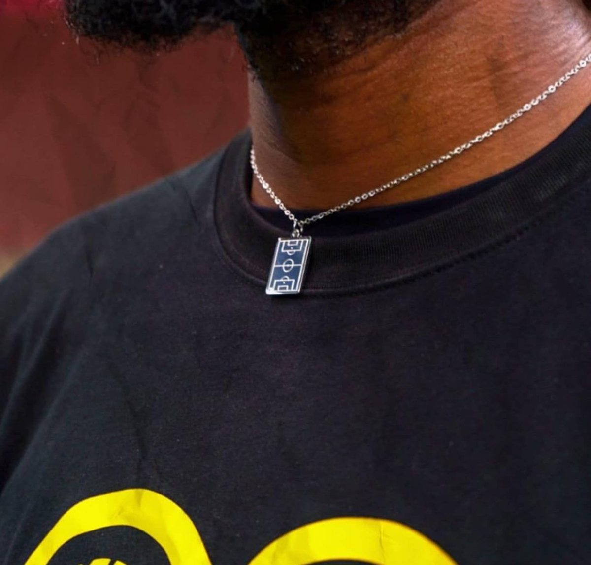 Silver Soccer Field Necklace worn against a club backdrop