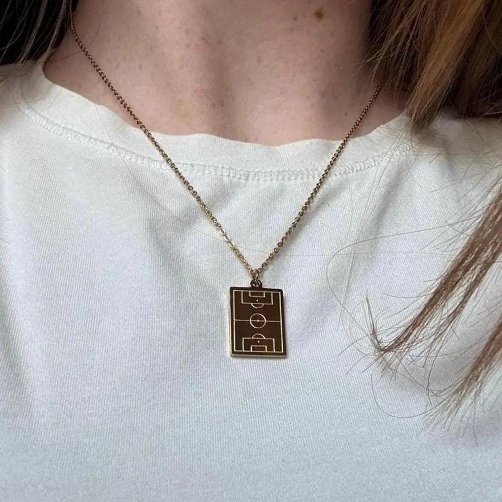 Gold soccer pitch pendant worn with a white tee