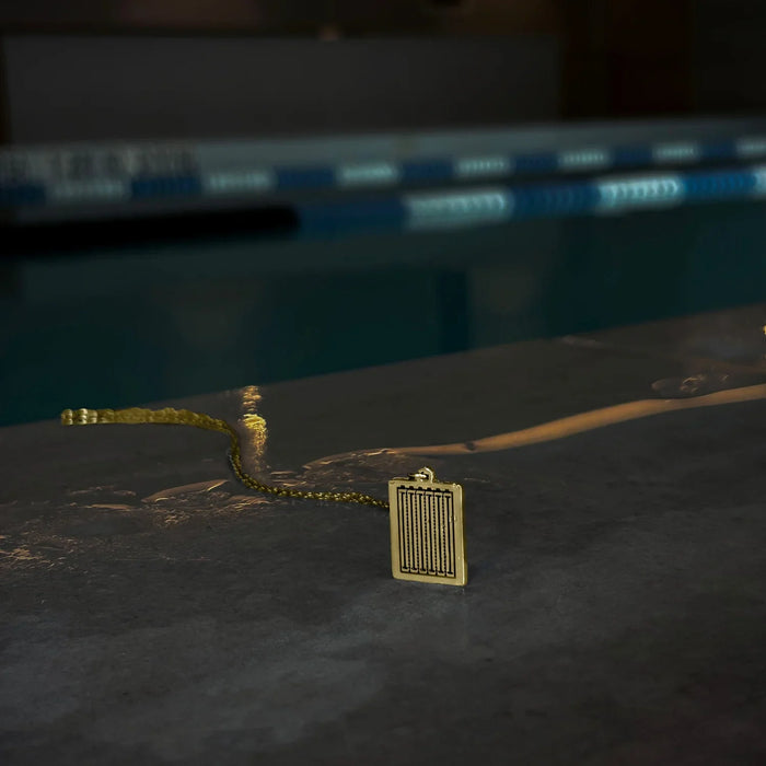 Gold pitch pendant on a stone ledge beside a pool